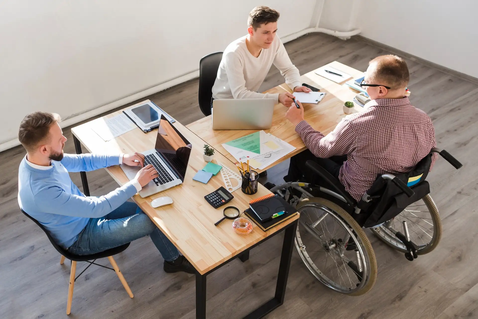Three people at a table one in a wheel chair, they are planning a meeting